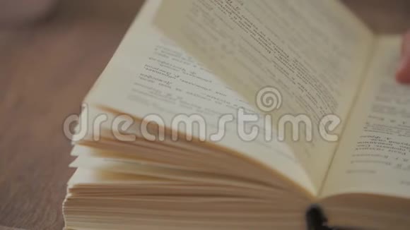 女人的手拿着一本书在阅读教育休闲读物时手指在书页上移动视频的预览图