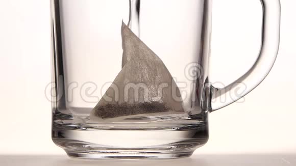 杯中的金字塔茶袋倒在沸水上视频的预览图