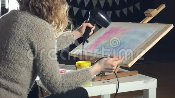 成年妇女用彩色水彩颜料作画在艺术学校用吹风机吹干视频的预览图