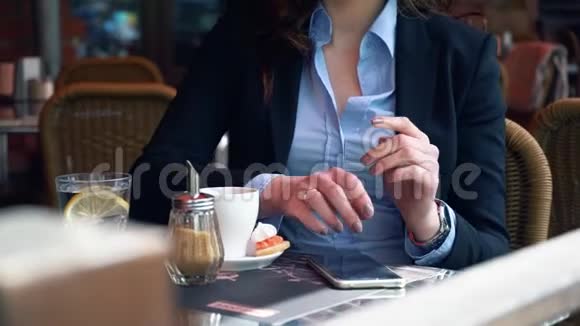 迷人的女商人穿着西装在户外咖啡厅用智能手机喝着咖啡慢动作专业的视频的预览图