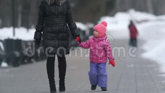 可爱的小女孩和她的母亲在冬天的街道上散步视频的预览图