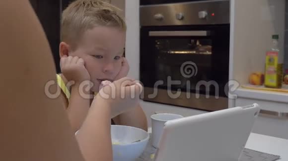妈妈一边喂孩子一边看平板电脑视频的预览图
