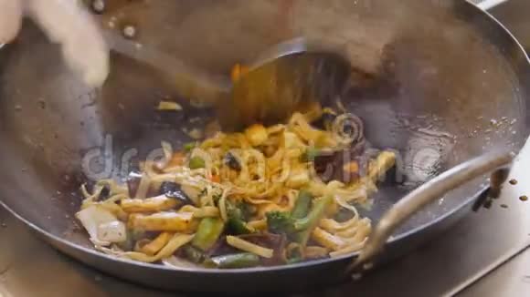 在街头美食节上专业厨师用豆腐和面条炒蔬菜烹饪过程接近视频的预览图