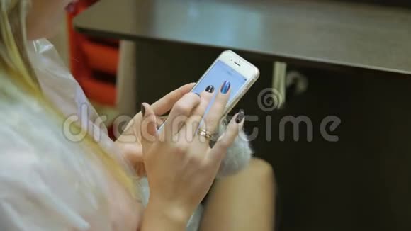 有魅力的女人在美发沙龙里染发时带着手机视频的预览图