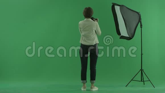 一位年轻女子在绿色屏幕上的侧面给观众拍照视频的预览图