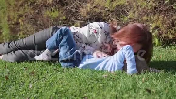 幸福的家庭在草坪上休息母亲用温柔和爱拥抱她的孩子儿子笑了快乐的童年视频的预览图