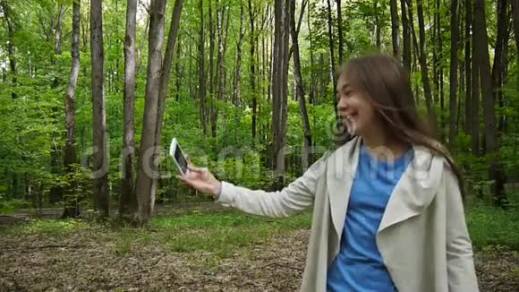 女孩在公园夏天拍自拍照片智能手机噗嗤笑了视频拍摄静态摄像机视频的预览图
