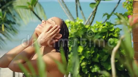 美丽的年轻黑发女子在室外淋浴性感和诱惑的人在暑假会慢慢洗衣服视频的预览图