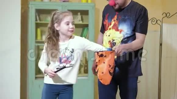 小丑用一根魔杖和一个包给女孩看一个魔术视频的预览图