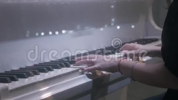 女音乐家手推着白色钢琴琴键在晚上的音乐厅视频的预览图
