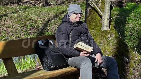 有两本书的人坐在长椅上视频的预览图