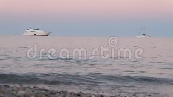 海滩上有一艘白色的游艇在宁静的夜晚在海浪中摇曳视频的预览图