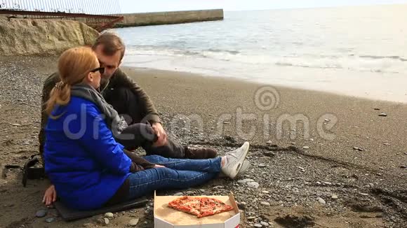 一对夫妇在海边吃披萨天气寒冷在一起视频的预览图