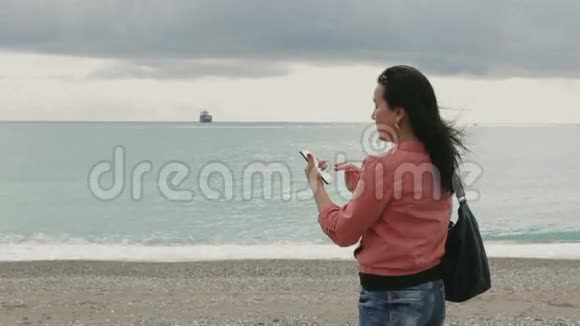 女人在做风景摄影一位手持智能手机的女士在阴天拍摄风景照片她站在视频的预览图