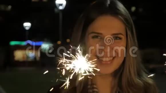 晚上在街上笑着的十几岁的女孩带着火花庆祝新年的年轻女子视频的预览图