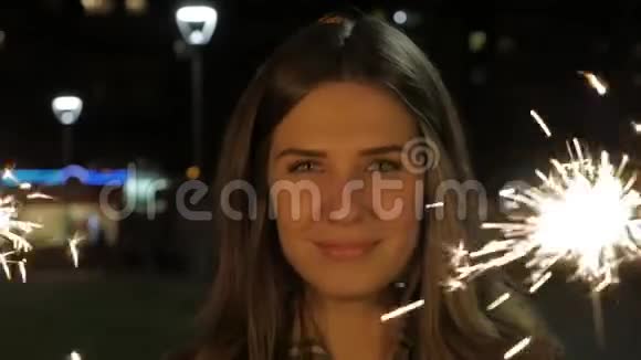 晚上在街上笑着的十几岁的女孩带着火花庆祝新年的年轻女子视频的预览图