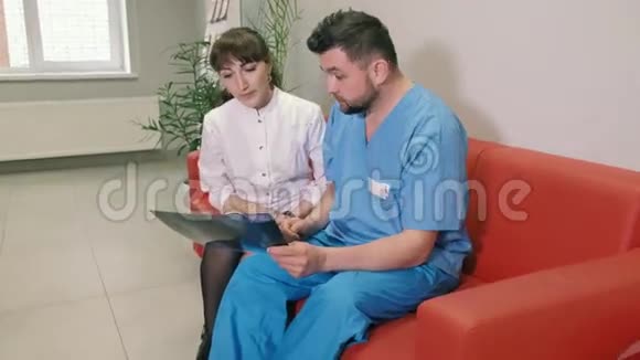 两个医生一男一女正坐在诊所的沙发上交谈4k视频的预览图