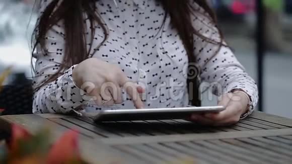 英俊的女人坐在木桌旁玩平板电脑视频的预览图