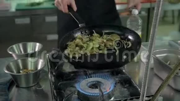 餐厅的厨师在厨房的平底锅里准备炒菜过滤图像视频的预览图