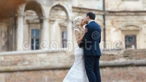 在中世纪城堡的背景下美丽的新娘和新郎幸福地接吻视频的预览图