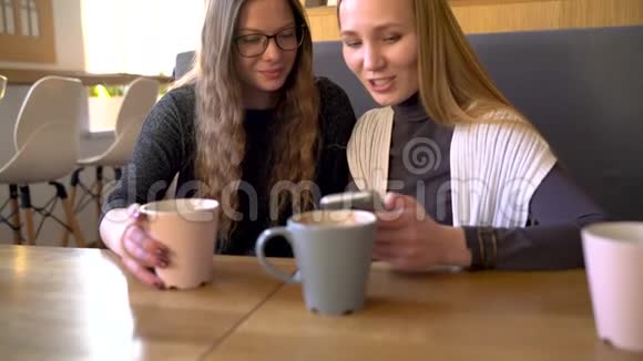 两个朋友的女人在咖啡馆里用手机交流视频的预览图