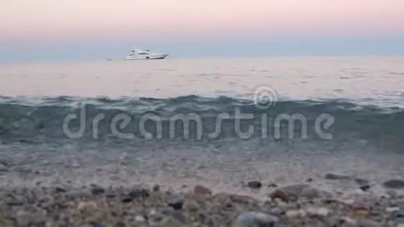 海滩上有一艘白色的游艇在宁静的夜晚在海浪中摇曳视频的预览图
