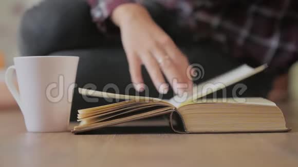 女人的手拿着一本书在阅读教育休闲读物时手指在书页上移动视频的预览图