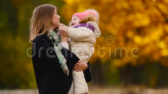 秋天当黄叶绕着妈妈和女孩玩枫叶时笑着笑着妈妈拥抱和玩耍视频的预览图