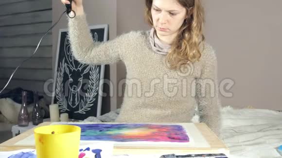 成年妇女用彩色水彩颜料作画在艺术学校用吹风机吹干视频的预览图