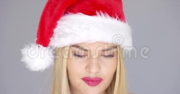 特写圣诞老人帽子里美丽的金发女孩的肖像视频的预览图