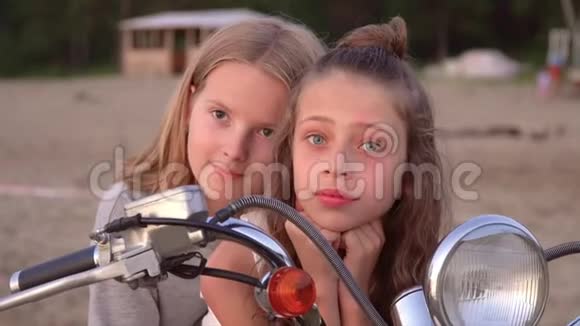 两个姐妹在一起玩得很开心两个女孩在白色脚踏车的海滩上摆姿势视频的预览图