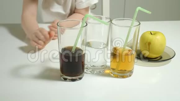 一个可爱的小女孩坐在一张桌子旁选择喝什么可乐或果汁健康生活方式的概念视频的预览图