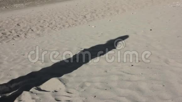 在一个瘦小女孩的沙滩上的影子和风中的帕雷奥视频的预览图
