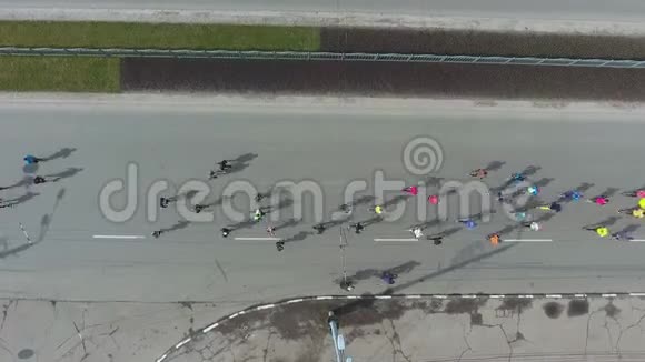 在城市道路上跑马拉松的运动员的高空向下射击视频的预览图