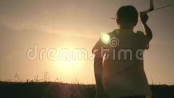两个男孩在日落时玩一架木飞机儿童玩飞机的剪影飞行的梦想概念视频的预览图