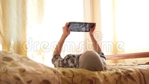 年轻的阿拉伯女孩带着平板电脑在家里卧室的床上女人反映在屏幕上技术与人的概念视频的预览图