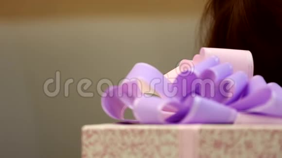 可爱的小快乐的女孩孩子看起来拿着一个巨大的礼物盒包裹着紫色的丝带蝴蝶结视频的预览图