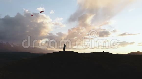 女剪影山金色晚霞天空放飞长尾玩具风筝1080p慢运动视频的预览图