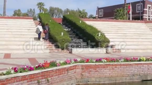 夏天一对母女在公园喷泉附近走下楼梯视频的预览图