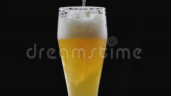 啤酒在黑色背景下倒入玻璃中啤酒杯中的气泡和泡沫泡沫滑下啤酒杯视频的预览图
