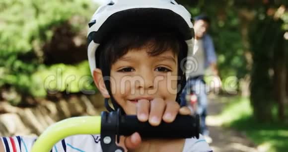 公园里戴自行车头盔的微笑男孩的肖像视频的预览图