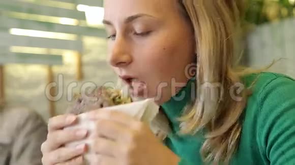 在咖啡厅吃素食汉堡的年轻女性视频的预览图