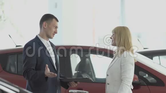 快乐女商人从汽车经销商的推销员那里得到汽车钥匙视频的预览图