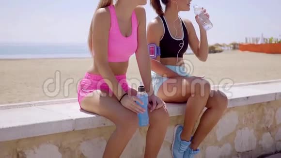 两个运动的年轻女人停下来喝一杯视频的预览图