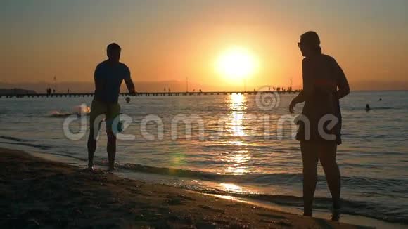 日落时分一对夫妇在海滩上打网球视频的预览图