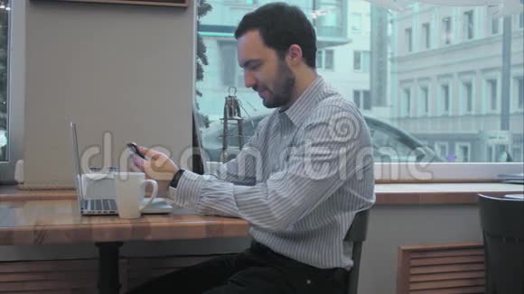 成功的年轻商人在咖啡休息时使用手机视频的预览图