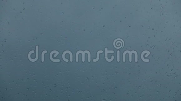 雨落在窗户上乌云密布的天空玻璃上的特写水滴视频的预览图