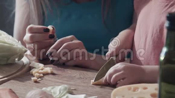 女儿与母亲在木板上切奶酪的特写视频的预览图