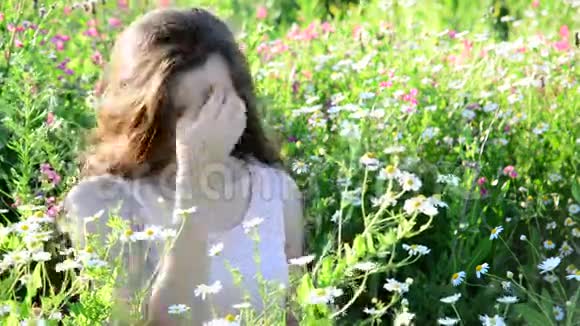 美丽的女孩在夏天的草地上看到雏菊视频的预览图