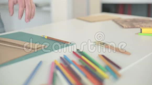 男人的手用尺子和刀剪下来桌子上的棕色纸用彩色铅笔视频的预览图